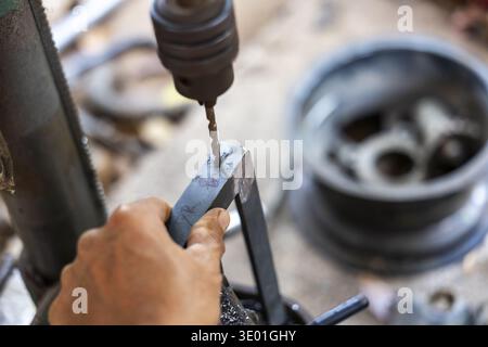 Focused craftsman hand using an industrial drill press machine for metal work. close up of tool making hole in workshop, showing precision and skill Stock Photo