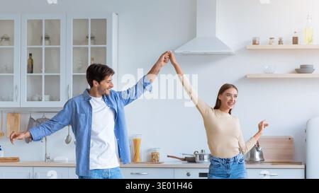 Couple Enjoys a Fun Dance in Their Bright Kitchen While Cooking Together Stock Photo