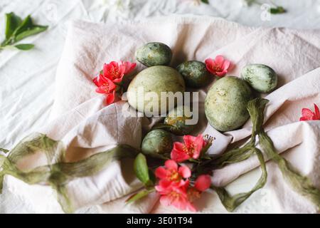 Happy Easter! Stylish natural dyed eggs and spring flowers on linen napkin on plate. Easter celebration table setting, holiday still life. Greeting ca Stock Photo