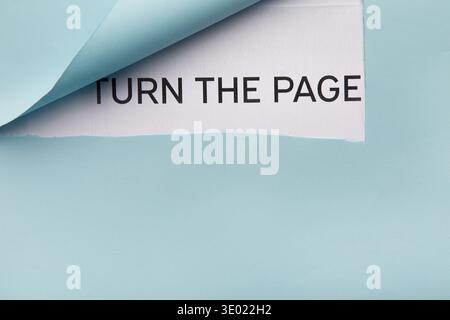 Text Turn the page on white paper behind blue folded corner Stock Photo