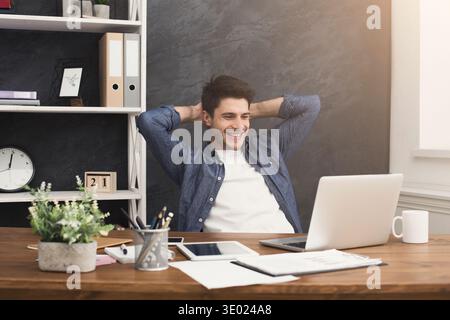 Young relaxed businessman with laptop in office Stock Photo