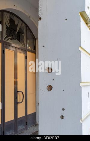 Irpin, Ukraine - 07 March 2026: View of a building facade scarred by destruction, where shattered glass contrasts with the stark grey wall riddled wit Stock Photo
