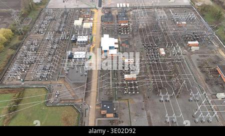 Aerial view of a vast electrical substation with its intricate network of lines, transformers, and buildings casting shadows on the ground, Burwell, U Stock Photo