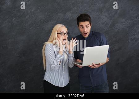 Shocked business partners using laptop at studio Stock Photo