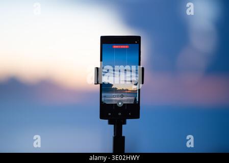 A mobile phone mounted on a tripod, against a blurred background of the ocean horizon, create content for social networks, use mobile photography and Stock Photo
