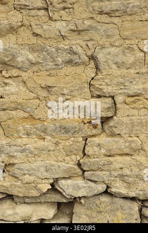 Stone wall texture forming an ancient rustic architectural background, displaying aged weathered rough surface with mortar. Cotswolds, England, United Stock Photo