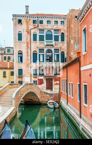 Venice canal in old town with historic buildings, small brick bridge and gondolas in traditional Italian cityscape. everyday transport and traditional Stock Photo