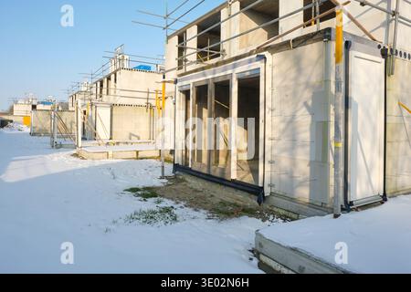 Construction site with residential houses under construction in the Netherlands on a sunny day during winter with snow under a blue sky. Stock Photo