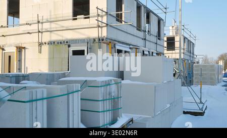 Construction site with residential houses under construction in the Netherlands on a sunny day during winter with snow under a blue sky. Stock Photo