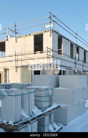 Construction site with residential houses under construction in the Netherlands on a sunny day during winter with snow under a blue sky. Stock Photo