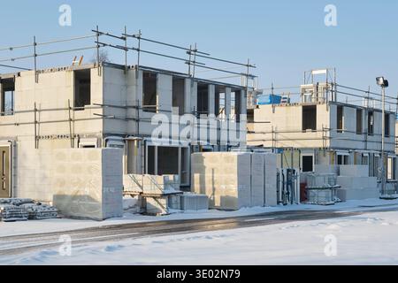 Construction site with residential houses under construction in the Netherlands on a sunny day during winter with snow under a blue sky. Stock Photo