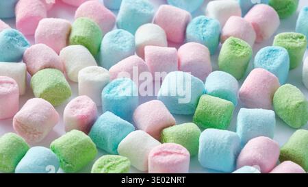 Background pattern of small mini marshmallows in pastel colors like green, pink, blue and white on a white background. Stock Photo