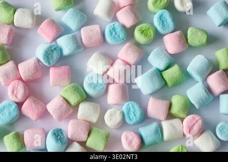 Background pattern of small mini marshmallows in pastel colors like green, pink, blue and white on a white background. Stock Photo