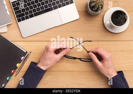 Man holding glasses while working on laptop Stock Photo