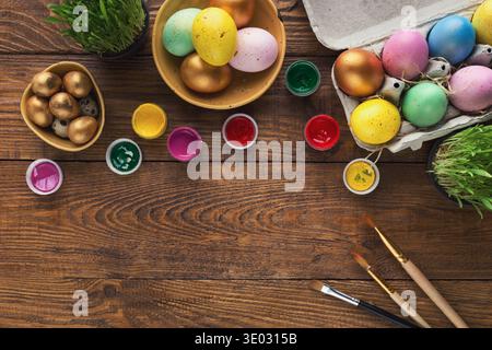 Painted easter eggs and brushes on wooden table Stock Photo