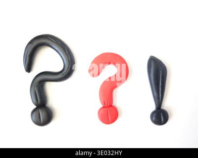 Three symbols made from modeling clay are arranged in a row on a white surface, showing a mix of colors and shapes. Stock Photo