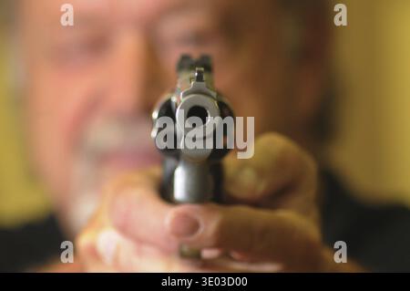Revolver shooter, man holding a gun and pointing at target Stock Photo