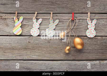 Easter paper rabbits and golden eggs on rope Stock Photo