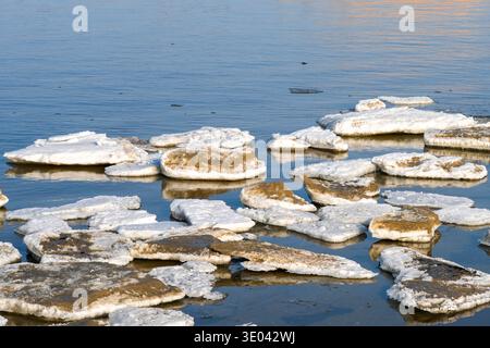 Broken ice floes floating on calm winter sea water, creating a cold seasonal landscape with reflections Stock Photo
