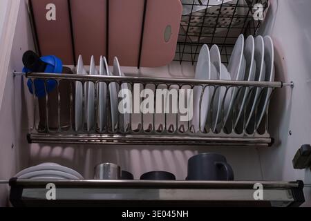 Porcelain Plates Drying After Washing In Kitchen. Organized Kitchen With Water Droplets And Stacked Utensils Visible. Scene Showing Porcelain Plates Stock Photo