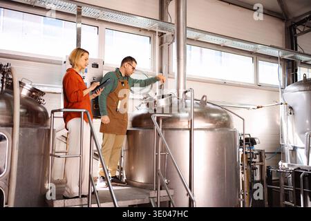 Brewery workers monitoring beer production in stainless vats Stock Photo