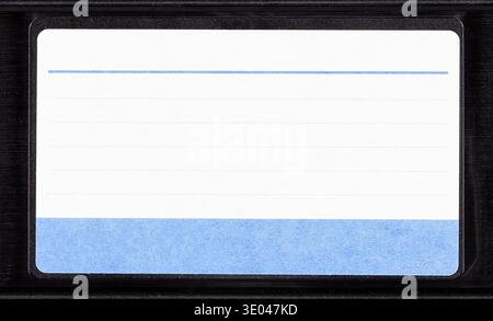 Blank VHS cassette label with blue lined sticker on black videotape cartridge, front view closeup isolated on white background, 80s 90s retro analog h Stock Photo