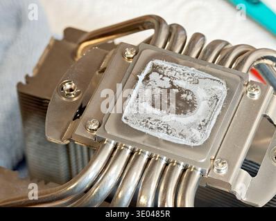 Dried out old thermal paste residue on the bottom contact plate of a modern desktop PC CPU air cooler with heatpipes, macro closeup of used computer c Stock Photo