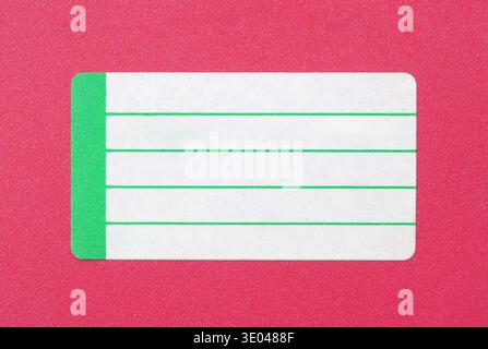 Blank green and white name label sticker with ruled lines on bright pink background, minimal closeup of empty address tag template, copy space for tex Stock Photo