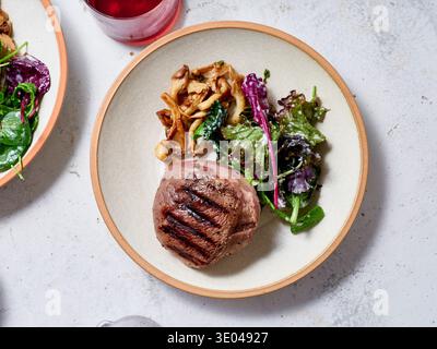 A gourmet keto meal featuring a perfectly grilled steak, sauteed mushrooms, and a fresh salad of leafy greens. Ideal for low-carb and ketogenic diet e Stock Photo