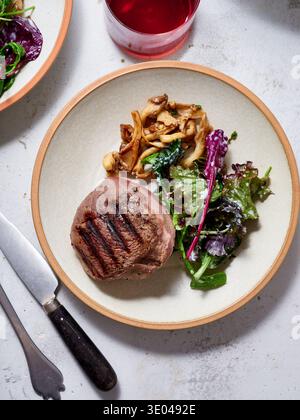 A delectable grilled steak served with sauteed mushrooms and mixed greens, perfect for a keto diet. The plate offers a balanced, protein-rich meal acc Stock Photo
