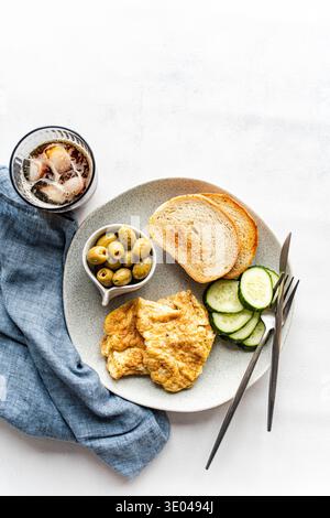 A delicious keto breakfast featuring scrambled eggs, fresh cucumber slices and Greek olives. Served with a side of toasted bread and a refreshing glas Stock Photo