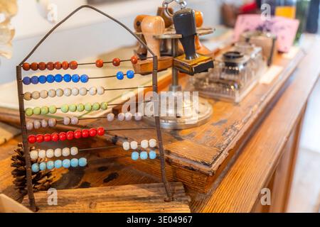 A colorful vintage abacus with wooden beads sits on a rustic wooden desk, accompanied by an assortment of retro office stamps, creating a nostalgic at Stock Photo