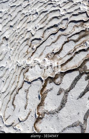Close-up view of natural travertine showcasing intricate wave patterns. The textured surface highlights the stone's unique formations, perfect for lux Stock Photo