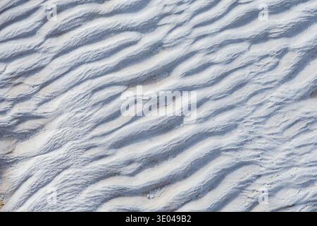 Close-up of natural travertine surface featuring wavy patterns in gray tones. Highlighting the texture and detail of the stone's formation, ideal for Stock Photo