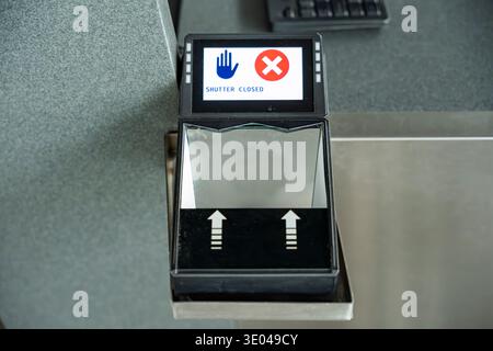 Close-up of a biometric scanner at an airport security checkpoint. The device displays a shutter closed warning, indicating restricted access in the s Stock Photo