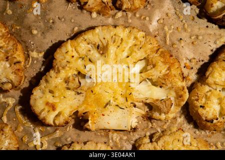 Close-up of roasted cauliflower steaks seasoned with herbs and spices, arranged on a sheet of parchment paper, showcasing a delicious and healthy plan Stock Photo