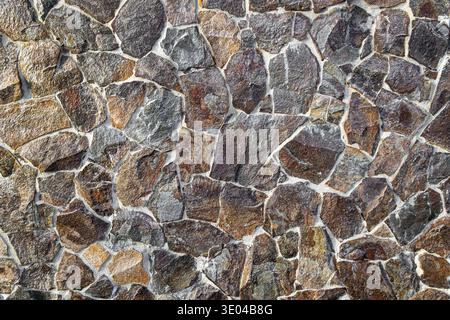 Irregular Stone Wall Texture Background Closeup. Close-up of an irregular natural stone wall with rough texture and mortar joints, ideal as an Stock Photo