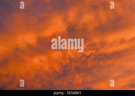 A mesmerizing abstract view of a sunset sky, filled with vibrant orange and purple clouds. The dramatic colors and textures set a tranquil mood, remin Stock Photo