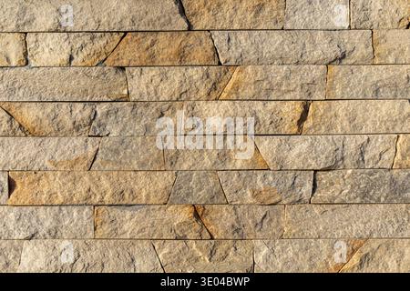Beige Stacked Stone Wall Texture Background. Close-up of a beige stacked stone wall with rough natural texture, creating a durable architectural Stock Photo