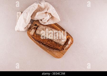 A rustic loaf of whole grain bread sits on a wooden board, exuding a freshly baked aroma. The bread's crunchy crust and soft interior complement the l Stock Photo