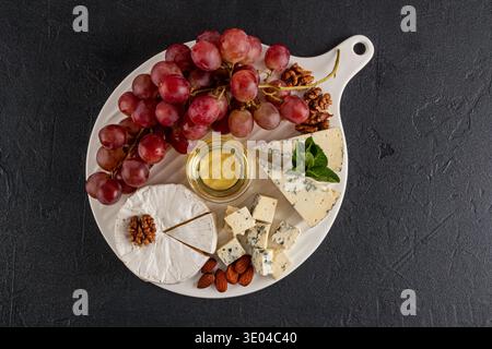 A delicious cheese platter featuring a selected assortment of cheeses, accompanied by fresh red grapes and a variety of nuts. Perfect for enjoying at Stock Photo