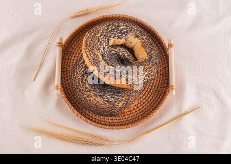 Two freshly baked whole grain bagels with poppy seeds rest on a woven basket. The rustic presentation highlights the fluffy texture and inviting aroma Stock Photo