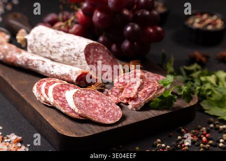 A cured salami with a white mold coating and a red string tie rests on ...