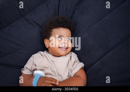 Happy toddler boy lying down smiling Stock Photo