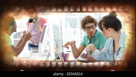 Collaborating four colleagues reviewing project on large monitor at shared desk, with sticky notes Stock Photo