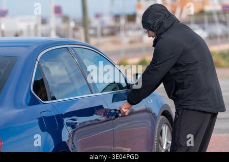 Man opening car door of blue sedan in parking area Stock Photo