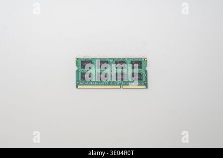 Close-up of a green DDR3 computer memory stick with black chips and gold contacts, isolated on white. Stock Photo
