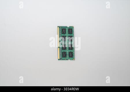 Close-up of a green DDR3 computer memory stick with black chips and gold contacts, isolated on white. Stock Photo