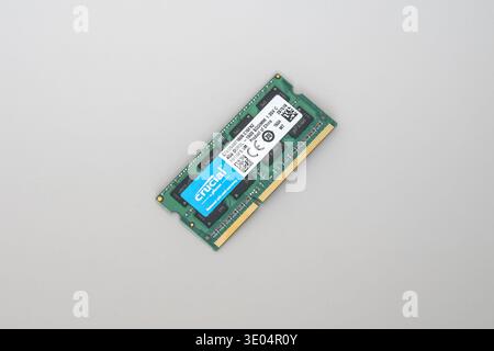 Close-up of a green Crucial DDR3 SODIMM memory stick with blue label, isolated on plain white surface. Stock Photo