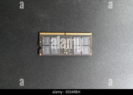 Close-up of a Crucial brand DDR5 RAM module showcasing memory chips and gold contacts against a dark textured surface. Stock Photo
